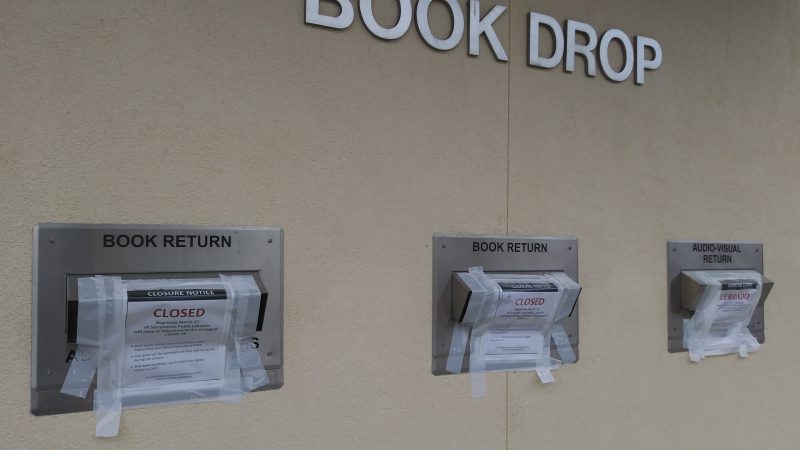 Three book drop window are taped shut with signs reading "closed".