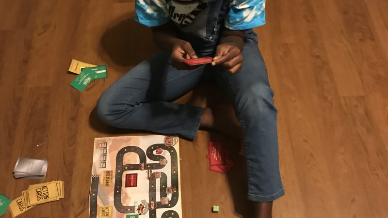 A girl sitting on the floor playing a board game.