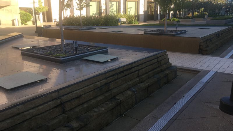 Two large, square fountains with no water in them at an outdoor mall.