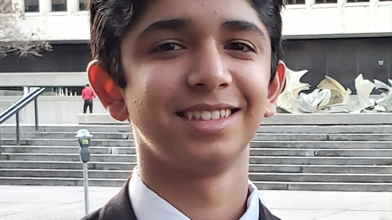 A boy in a suit and tie smiles at the camera.