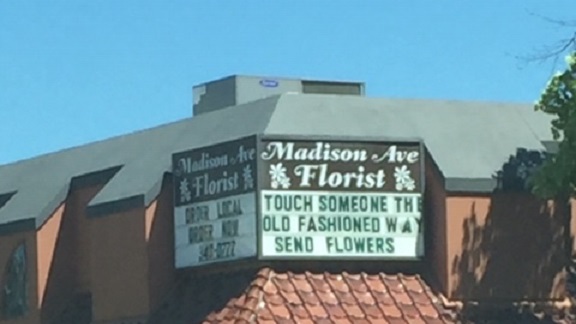 A bulletin board on a red building with a gray roof under blue skies.