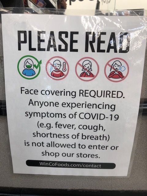 A colored sign on white paper is taped in a store window.