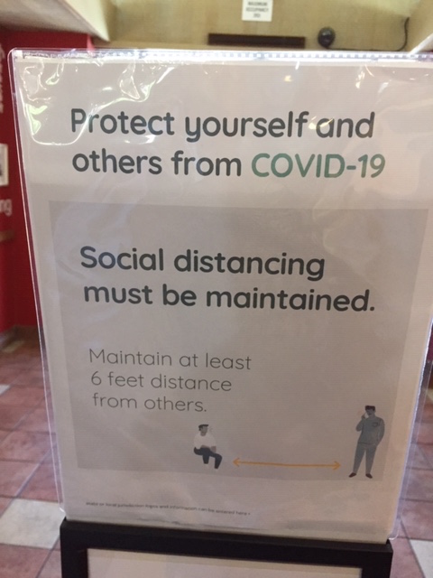 A sign on a stand notifies customers about social distancing requirements.