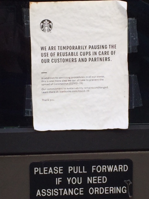 A white paper with black ink is taped on a window above a sign reading "Please pull forward if you need assistance ordering."