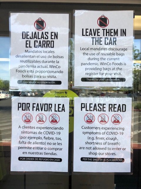 Four black and red signs are taped on the front door of a business.