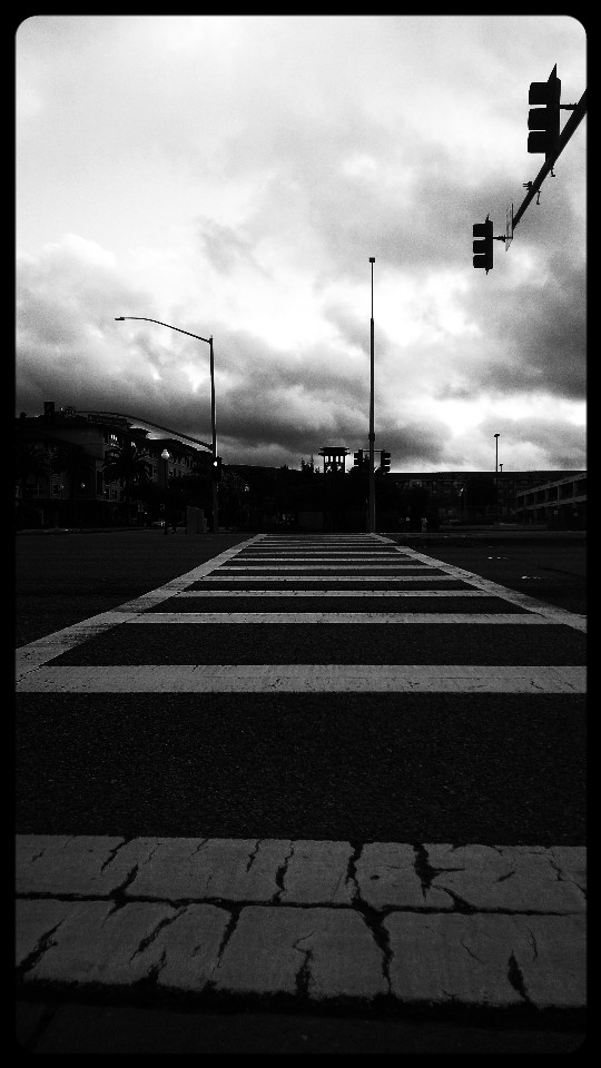 A black and white photograph of an empty street intersection.