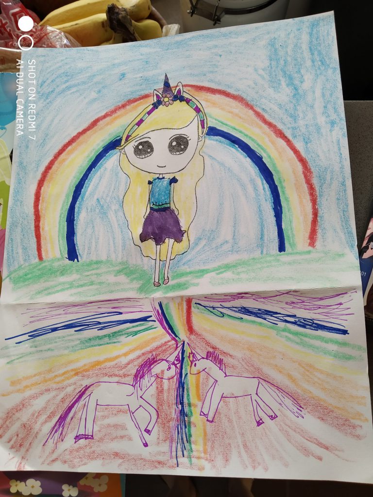 A children's drawing of a girl with long blonde hair standing in front of a rainbow, with two unicorns beneath her.