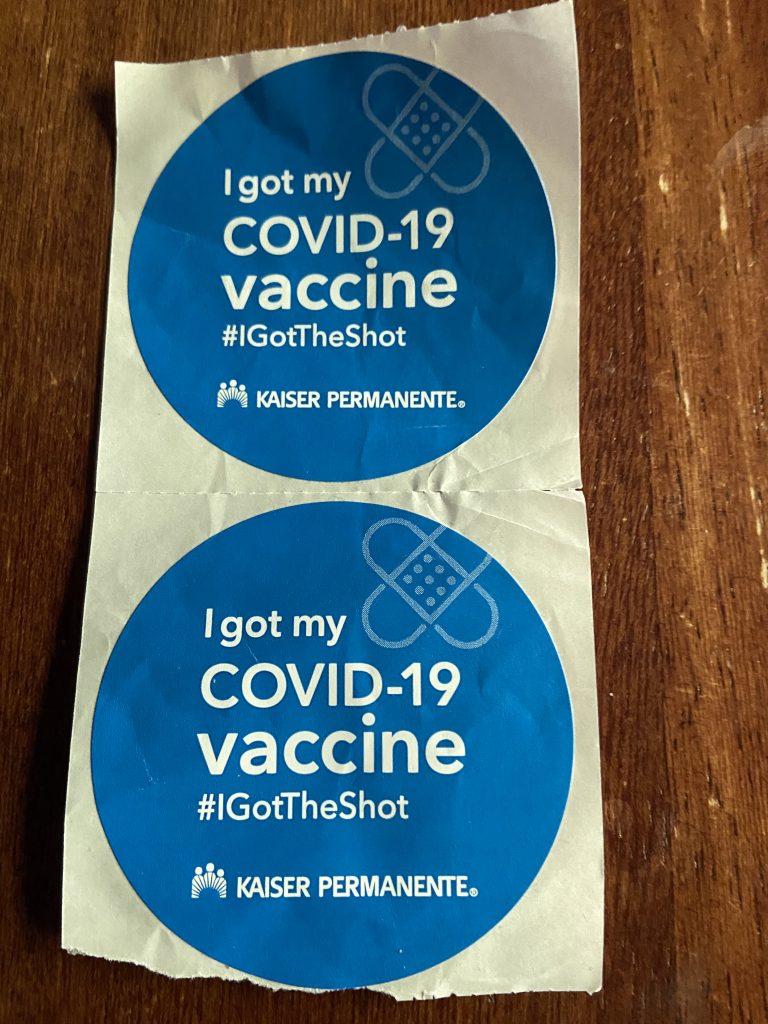 Two blue circular stickers that say "I got my COVID-19 vaccine #igottheshot Kaiser Permanente"